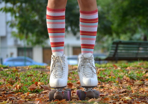 Close-up of a teenage girl in roller skates and striped knee high socks standing in an autumn park