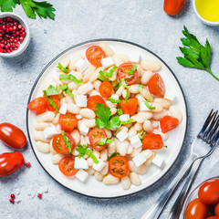 White bean tomato salad on concrete background. Top view, space for text.