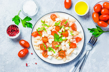White bean tomato salad on concrete background. Top view, space for text.