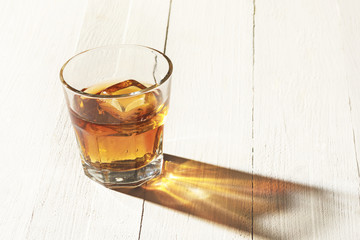 Whiskey in glass, ice cub served in a short glass on white table