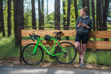 Girl on a bicycle with headphones in the park. A racing bicycle. Active way of life and playing sports.