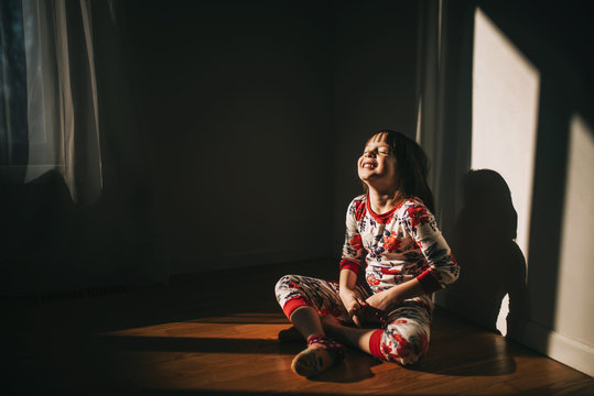 Girl sitting on the floor in her pyjamas laughing