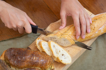 Chef is slicing brown delicious bread into pieces and ready to serve to customers in the bakery shop.