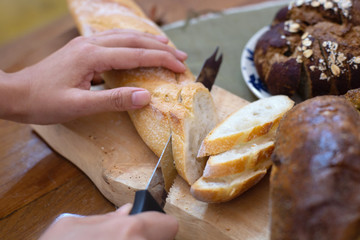 Chef is slicing brown delicious bread into pieces and ready to serve to customers in the bakery shop.