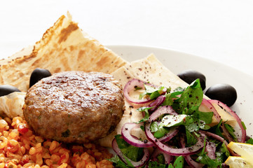 fried turkey cutlet on flat bread with bulgur pilaf, parsley onion salad, and olives