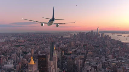 Poster AERIAL: Passenger airplane flying over downtown Manhattan at beautiful sunset. © helivideo