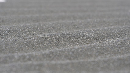 MACRO, DOF: Beautiful shot of black sand on exotic shore creating a wavy pattern