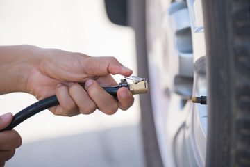 driver checking air pressure and filling air in the tires close up
