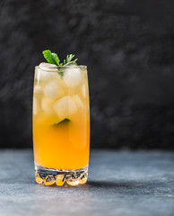 Fresh summer cocktail with orange juice and ice cubes. Glass of orange soda drink on dark background
