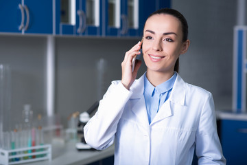 Young pretty scientist talking by cellphone and smiling.