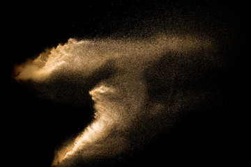 Golden sand explosion isolated on black background. Abstract sand cloud. Golden colored sand splash...