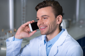 Young satisfied expert smiling and having phone conversation.