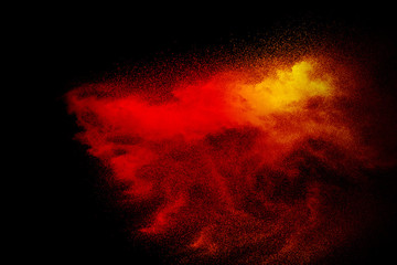 Abstract explosion of red dust  on black background. Abstract red powder splatter on dark  background. Freeze motion of red powder splash.