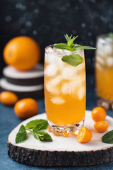Fresh summer cocktail with orange juice and ice cubes. Glass of orange soda drink on dark background