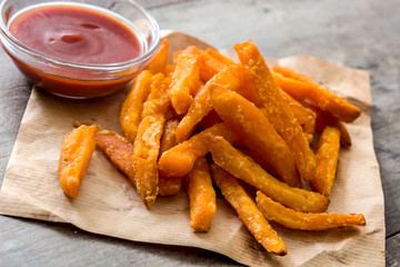 Sweet potato fries and ketchup sauce on wooden table
