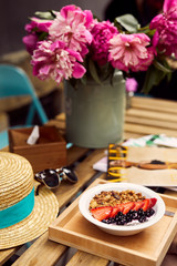 Pretty blonde girl eat her morning smoothie with flowers on the table