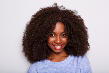 young african american woman with curly hair smiling against white wall