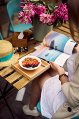 Pretty blonde girl eat her morning smoothie with flowers on the table