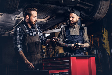 Fototapeta na wymiar Two mechanic talking during repairs a broken car in a garage.