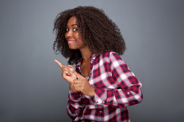  happy young african woman pointing finger at copy space on gray background