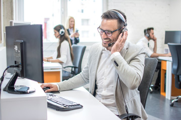 Portrait of happy smiling customer support phone operator at workplace.