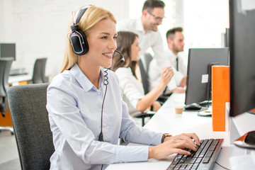 Smiling woman customer support operator using computer in office