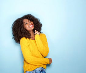 happy young african woman looking up on blue background