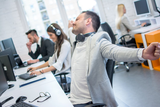 Businessman  Stretching Arms At The Desk In His Workplace Office.