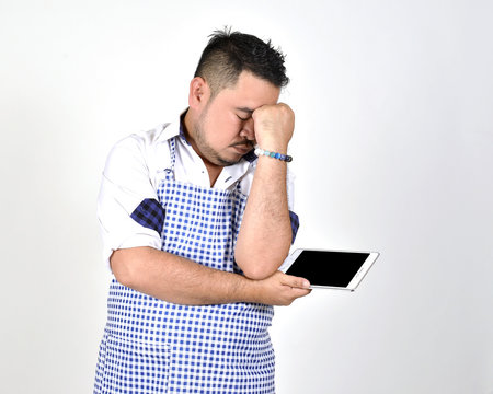 merchant Asian man in white and blue apron is feeling regret or boring
when get bad news from connection internet in tablet with white background