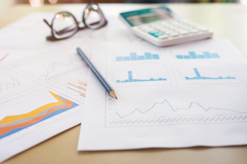 business office desk workplace report graph with pencil, calculator and eyeglasses on wooden table