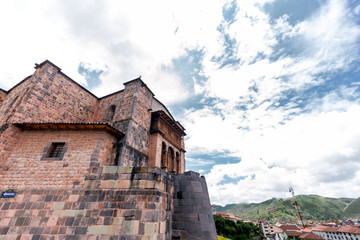 Front of the ruins of Qorikancha with city of Cusco (Peru) and mountains in the background