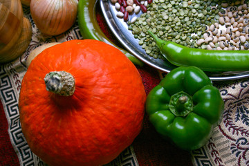 Halloween small yellow Pumpkin and Green pepper, onion, green peas, legumes on plate. Top view, close up