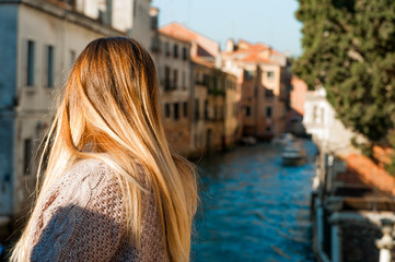 Fototapeta na wymiar young blond woman dressed in casual style looking at venice canal seen from behind