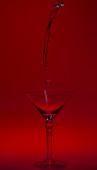 Martini glass high key photo in studio with red tint and water plash