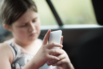 Beautiful girl sitting on the passenger seats in the car and using a smartphone