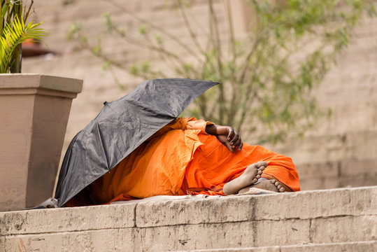 A hindu pilgrim sleeping under an umbrella on the ghats in Varanasi, India.