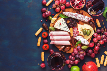 Fototapeta na wymiar Various appetizer-red wine, fruits,sausages,cheese, vegetables on a dark finem background. Copy space, top view.