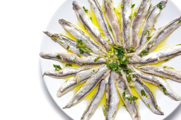 Delicious Marinated anchovies with parsley, olive oil and vinegar isolated on white background. Top view. Copy space.