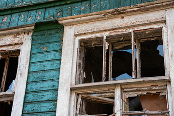 The broken window of a burned wooden building is close