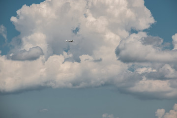 Little plane approaching into the blue Germany sky with white clouds