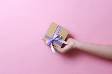 gift in female hands on a colored background. Holiday, minimalism, congratulations.