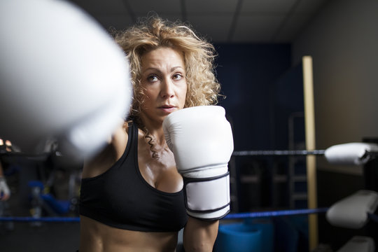 Serious woman training in gym with punching bag