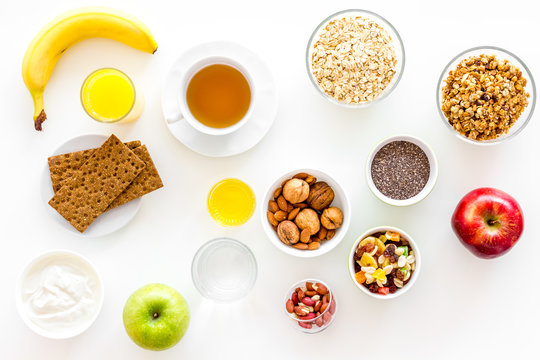 Ingredients for healthy breakfast. Fruits, oatmeal, yogurt, nuts, crispbreads, chia on white background top view