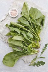 Fresh green spinach leaves and arugula with pink salt on a gray background. Top view