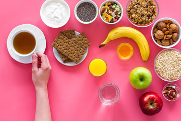 Fototapeta na wymiar Layout of products for healthy and hearty breakfast. Fruits, oatmeal, yogurt, nuts, crispbreads, chia on pink background top view