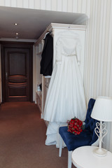 Fototapeta na wymiar Beautiful black grooms jacket and brides dress hanging in hotel room