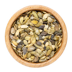 Pumpkin seeds in wooden bowl isolated on white. Top view.