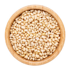Pine nuts in wooden bowl isolated on white. Top view.