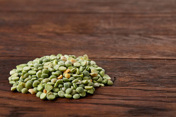 Pile of green peas on rustic wooden background, close-up, top view, selective focus.