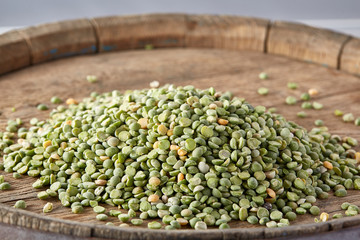 Pile of green peas on the top of wooden barrel, close-up, top view, selective focus.